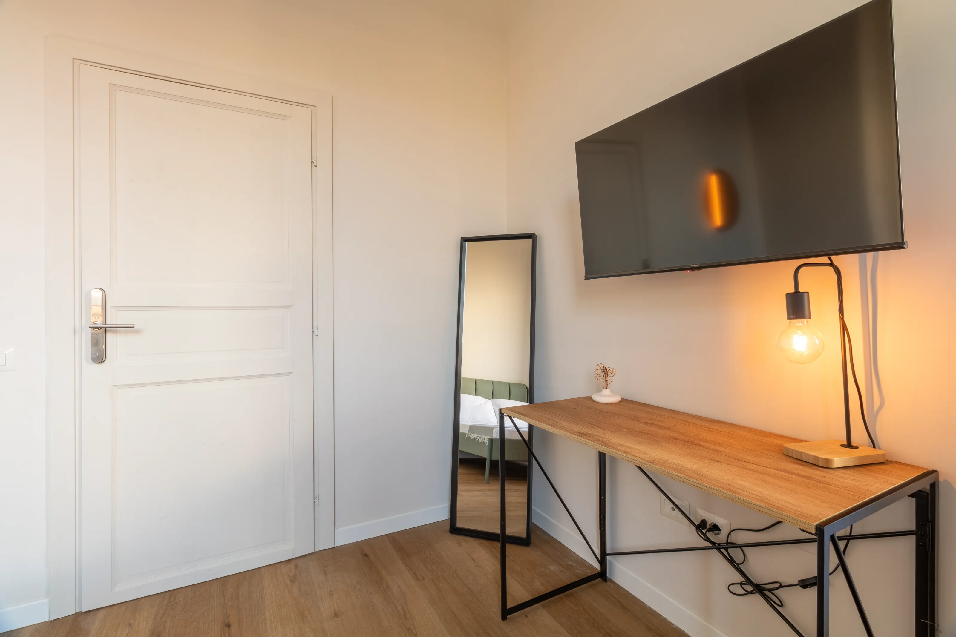 Minimal space with a wooden desk, full-length mirror, and warm lighting